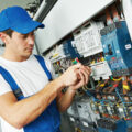Young adult electrician builder engineer screwing equipment in fuse box